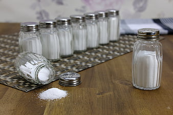 Glass Salt Shakers With Spilled Salt On Wooden Table