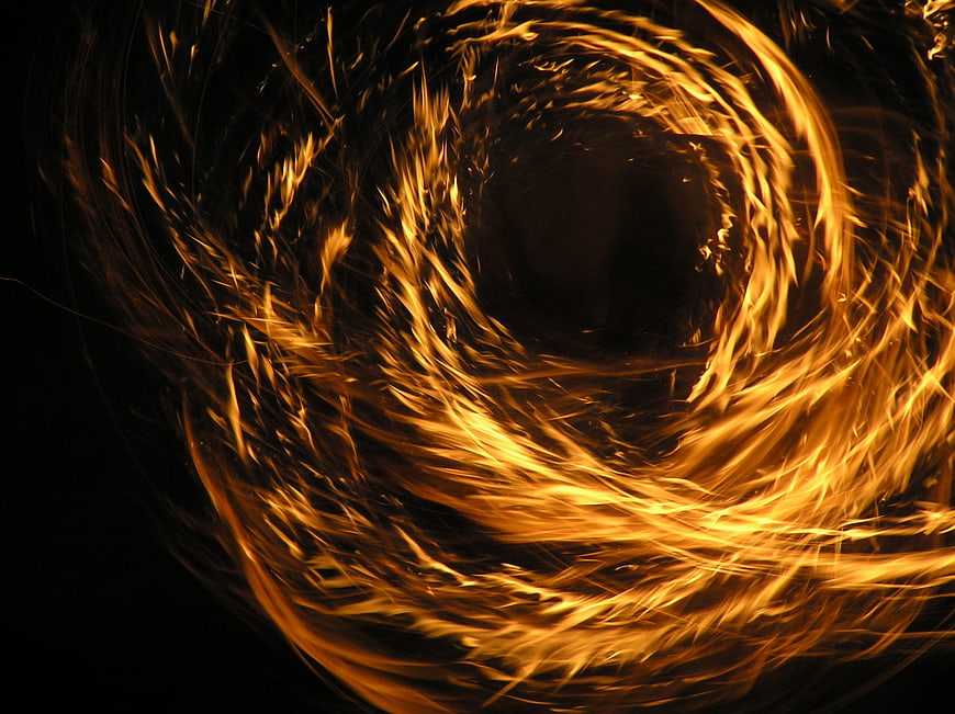 Abstract swirling fire vortex with golden sparks on black background
