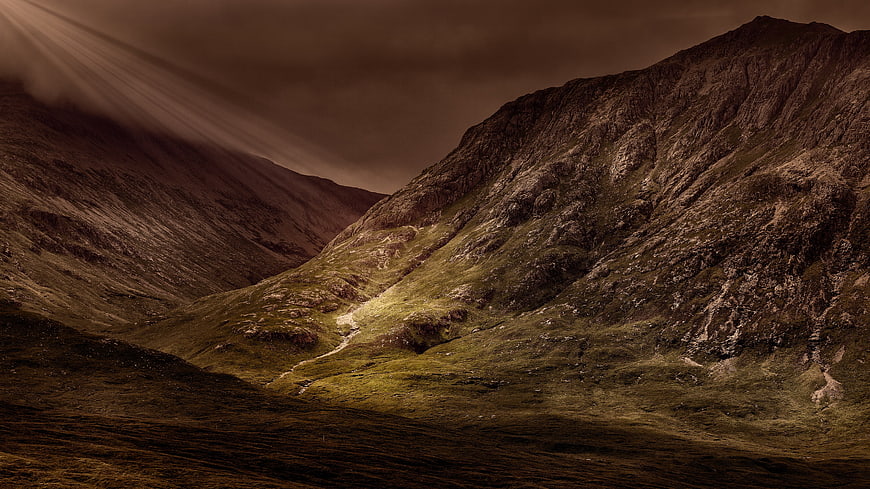 Dramatic mountain valley with sunbeams breaking through clouds