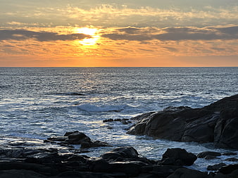 Golden Sunset Over Rocky Ocean Coastline with Waves