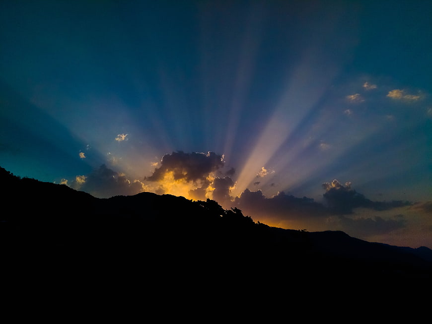 Dramatic Sun Rays Bursting Over Silhouetted Mountain Ridge