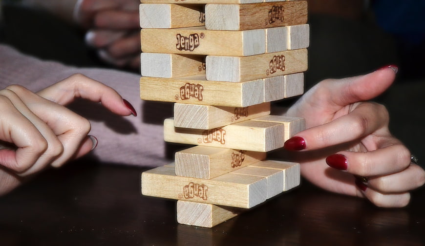 Jenga Tower Game With Hands And Red Nails