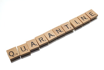 Quarantine spelled with wooden Scrabble tiles on white background