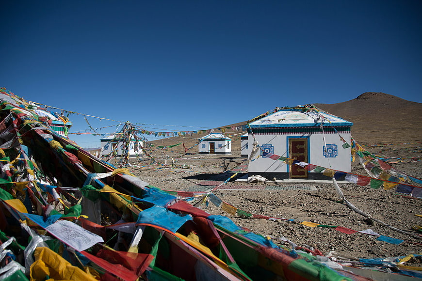 Tibetan prayer flags and white stupa in highland landscape