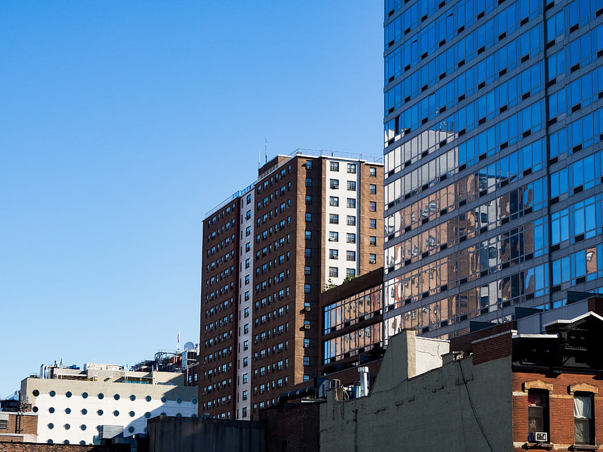 Modern Glass Skyscraper Reflecting Brick Buildings Against Blue Sky
