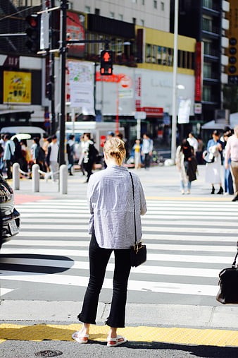 Woman in Striped Shirt Waiting at Busy City Crosswalk