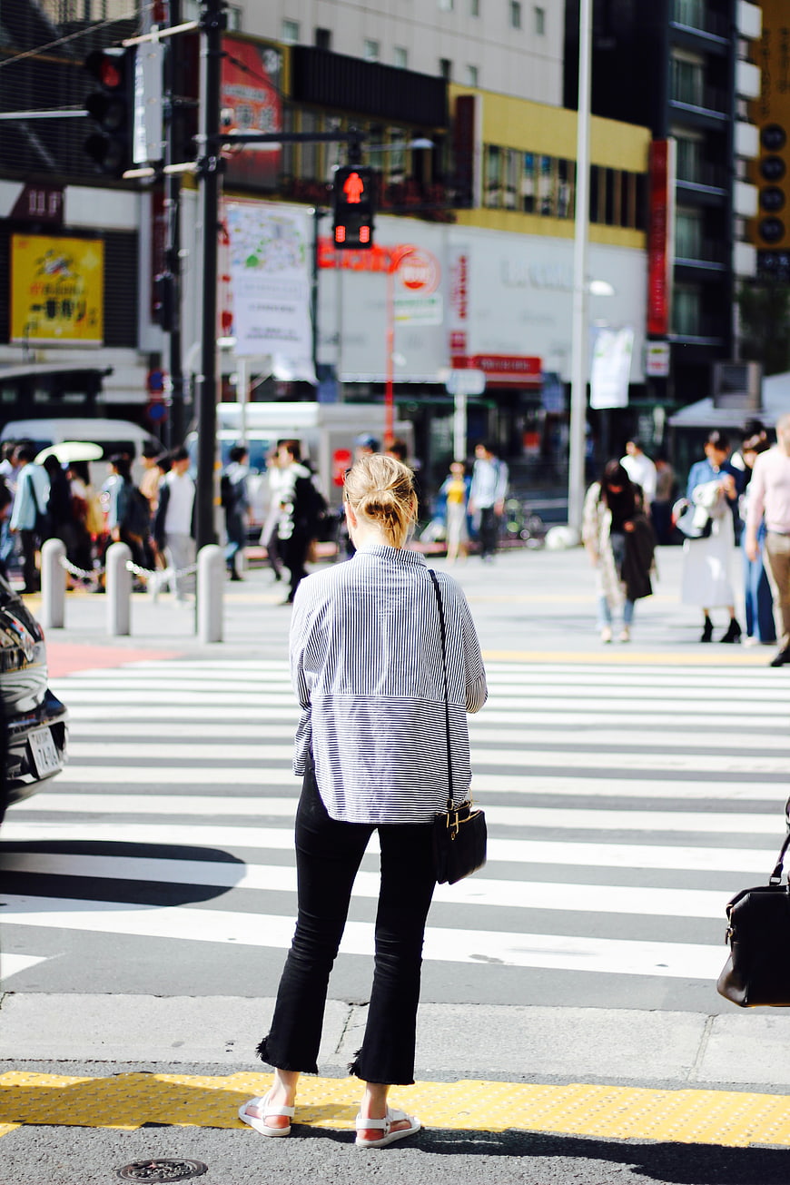 Woman in Striped Shirt Waiting at Busy City Crosswalk