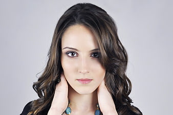 Studio Portrait Of Young Woman With Wavy Hair And Blue Necklace