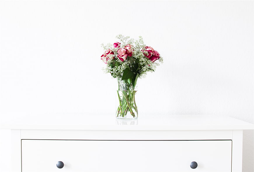 Pink Roses and Baby's Breath in Clear Glass Vase on White Dresser