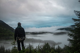 Man overlooking misty mountain lake landscape