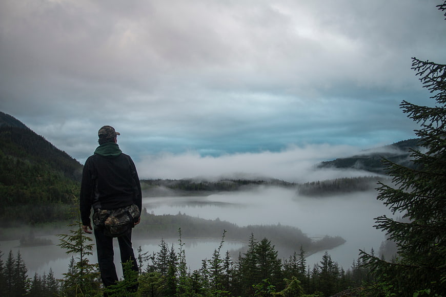 Man overlooking misty mountain lake landscape