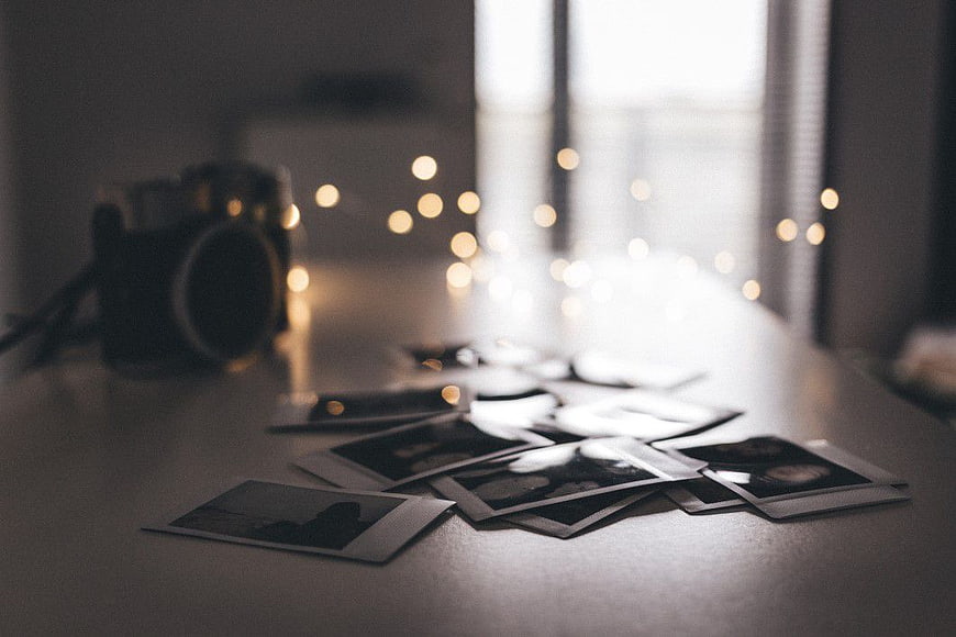 Scattered Polaroid Photos and Vintage Camera on Table