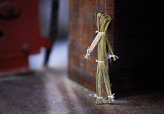 Handmade straw puppet leaning against rustic wooden post