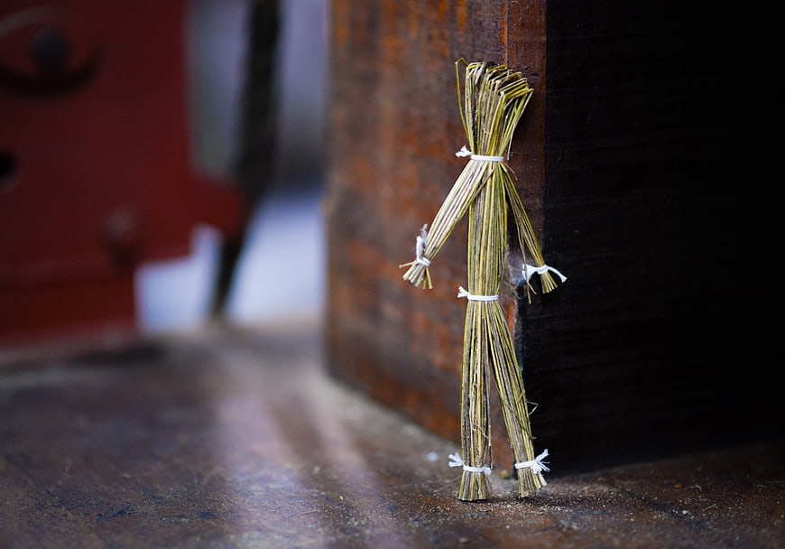 Handmade straw puppet leaning against rustic wooden post