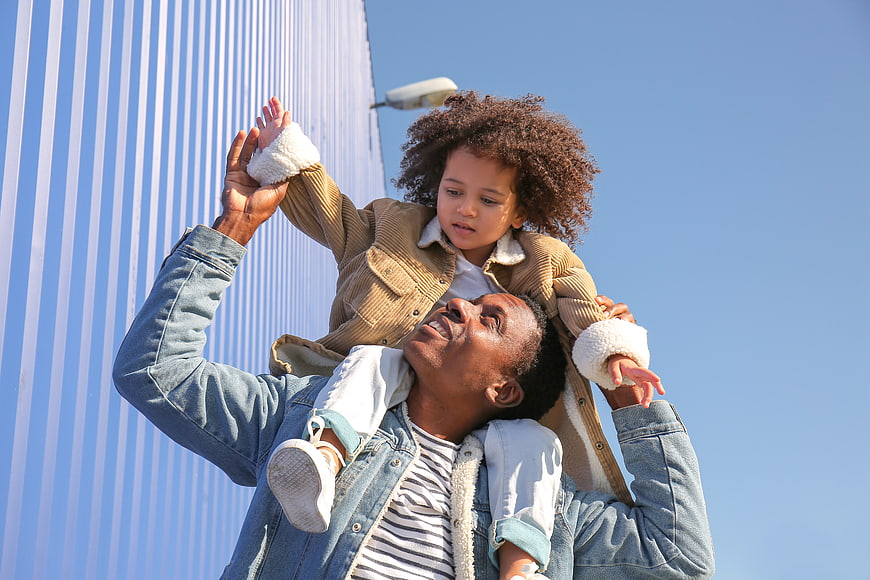 Father carrying child on shoulders outdoors