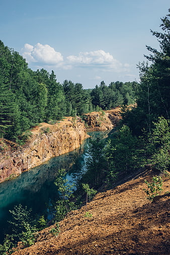 Turquoise quarry lake surrounded by pine forest and rocky cliffs
