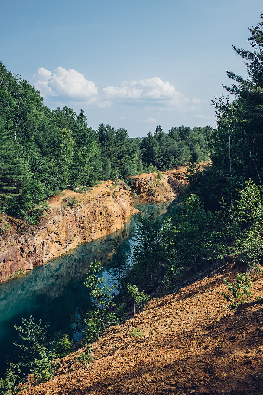 Turquoise quarry lake surrounded by pine forest and rocky cliffs