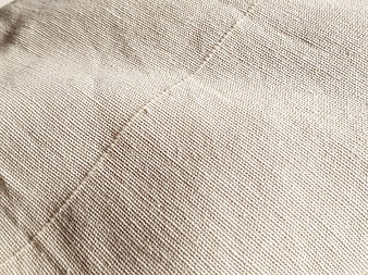 Close-up of beige woven fabric texture with stitching