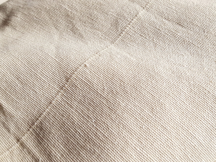 Close-up of beige woven fabric texture with stitching