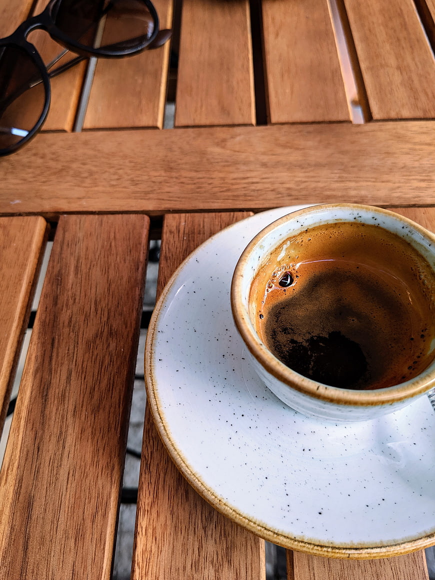 Espresso cup and sunglasses on wooden table