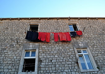 Red and blue laundry hanging on old stone building facade