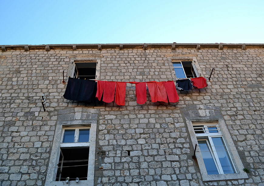 Red and blue laundry hanging on old stone building facade