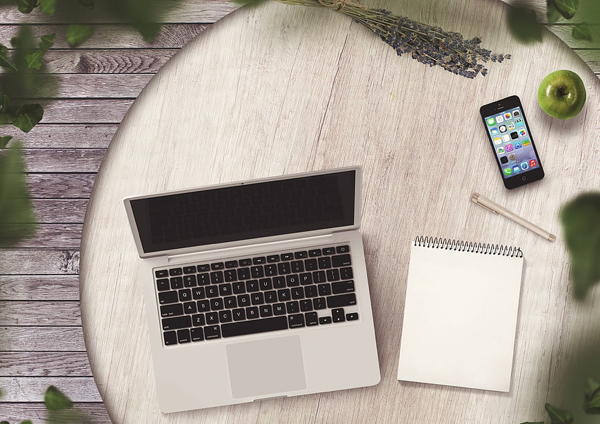 Flat lay workspace with laptop, smartphone, and notebook on wooden table