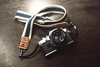 Vintage Olympus Camera with Striped Strap on Wood