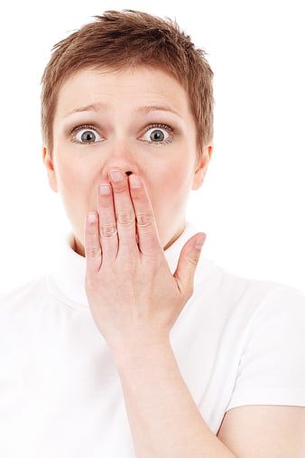 Surprised woman covering mouth with hand on white background