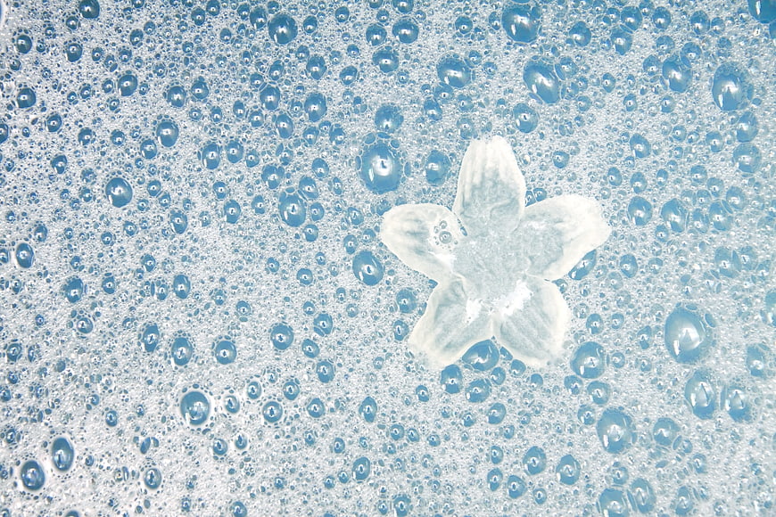 White flower floating in blue soapy bubbles background