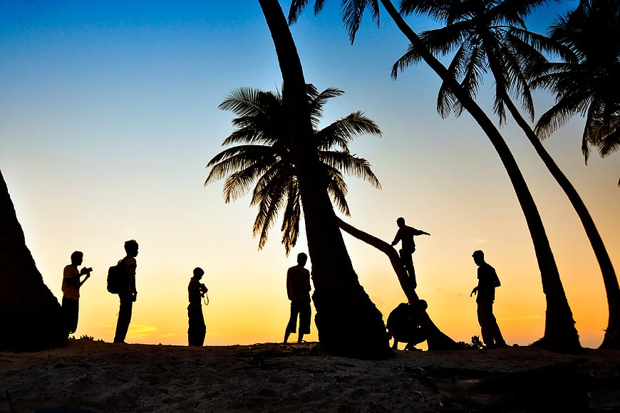 Silhouetted Friends On Beach At Sunset With Palm Trees