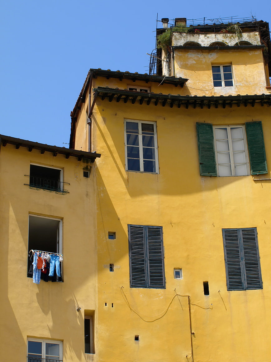 Yellow European Building Facade with Laundry and Shutters