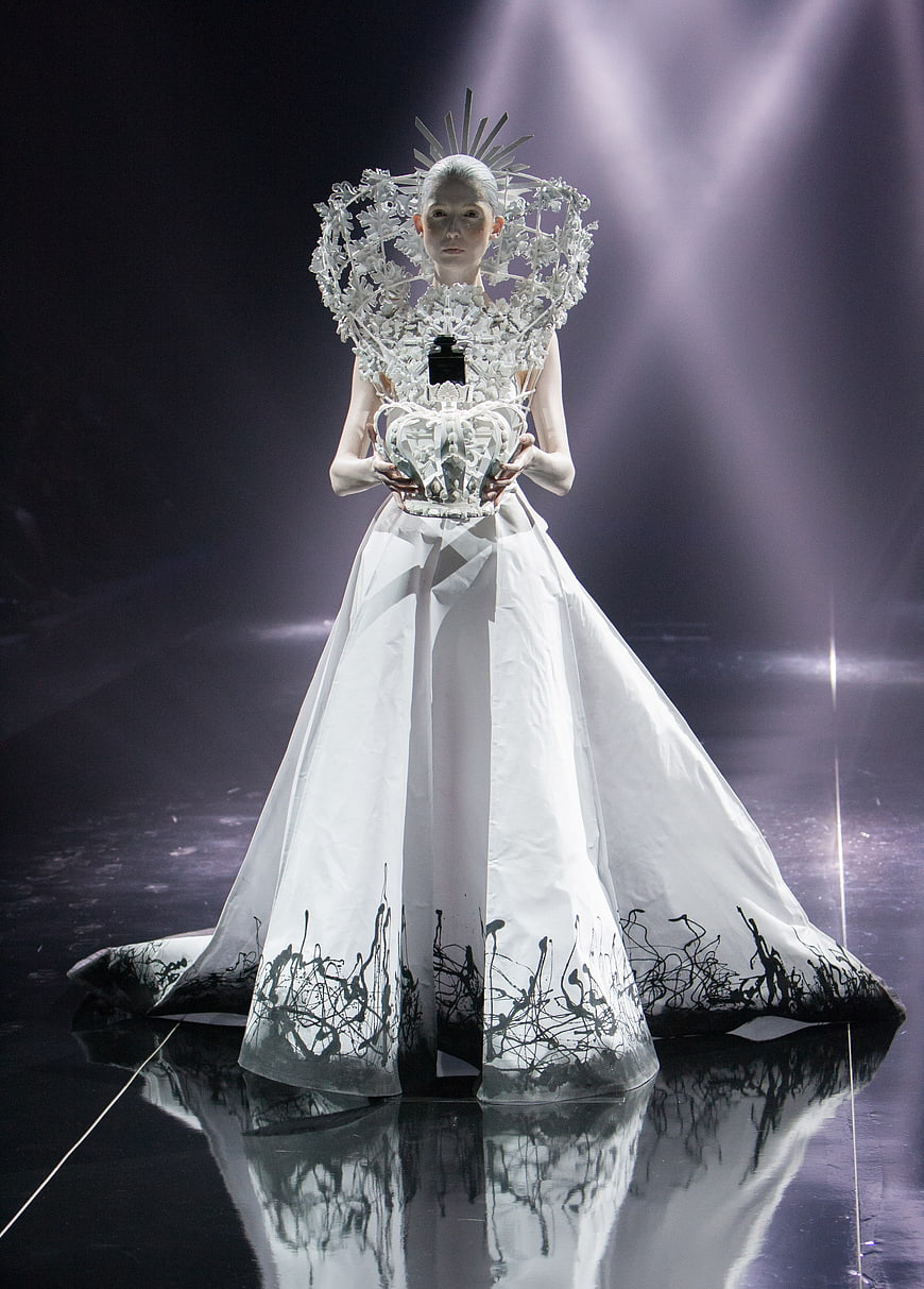 Avant-garde fashion model in white gown with black accents on runway