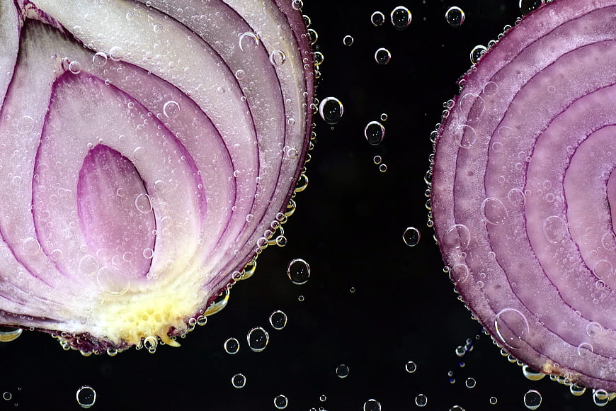Macro shot of red onion slices underwater with bubbles