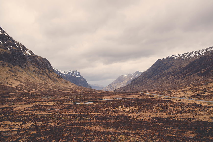 Scenic Highland Valley with Snow-Capped Mountains and Winding Road