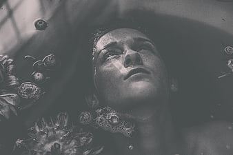 Woman relaxing in bath with flowers in black and white