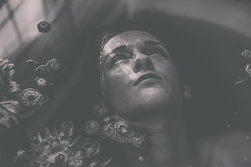 Woman relaxing in bath with flowers in black and white