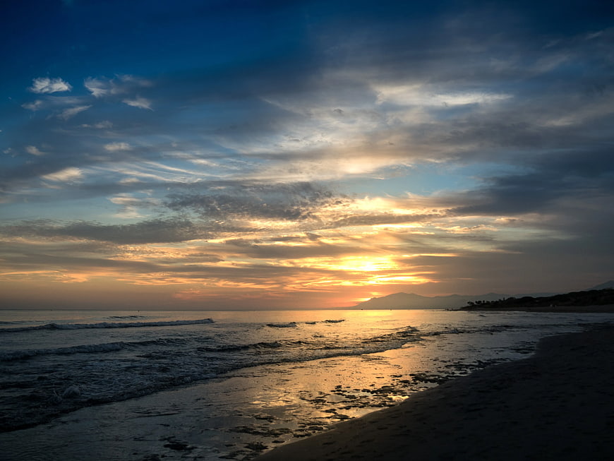 Dramatic Sunset Over Ocean Waves and Sandy Beach