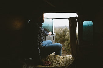 Man sitting in van looking out window at nature