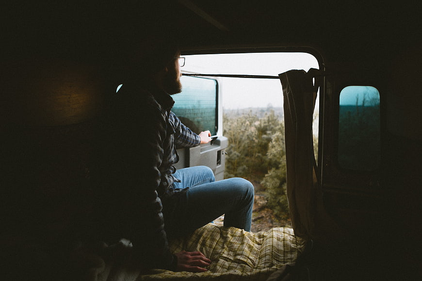 Man sitting in van looking out window at nature