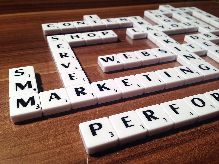 Scrabble Tiles Spelling Marketing and Website on Wooden Table