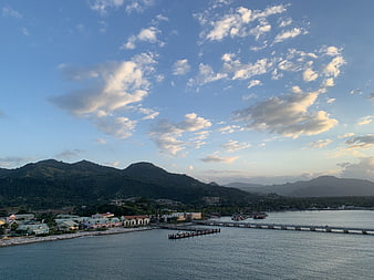 Scenic coastal town with pier and mountains at sunset