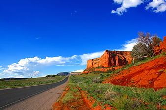Red Rock Cliffs Along Desert Highway Under Blue Sky