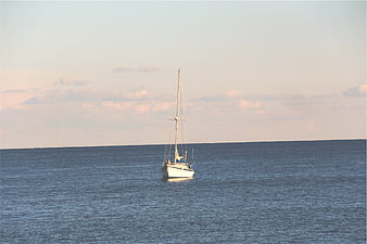 Lone Sailboat on Calm Ocean at Sunset