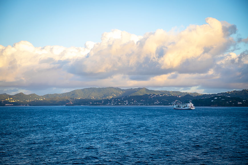 Ferry boat sailing on blue ocean with mountains and clouds