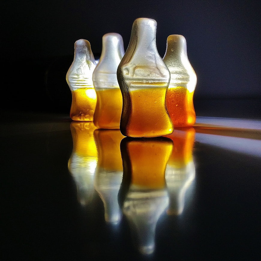 Gummy Cola Bottles on Reflective Black Surface