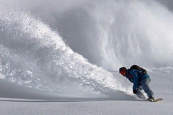 Snowboarder carving through deep powder snow spray
