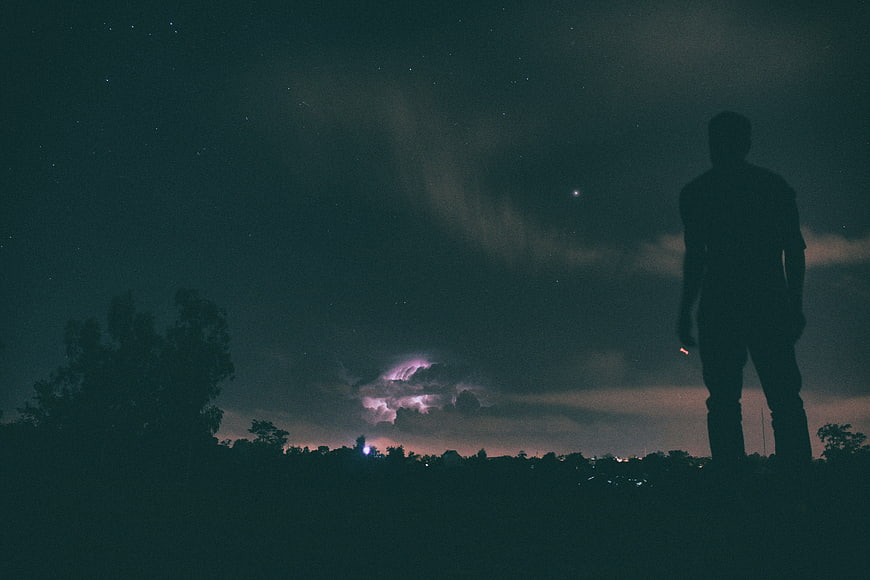 Silhouette of Man Standing Under Starry Night Sky