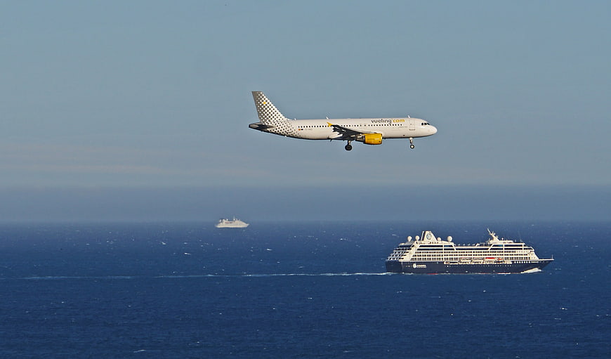 Vueling airplane landing over cruise ship in Mediterranean sea