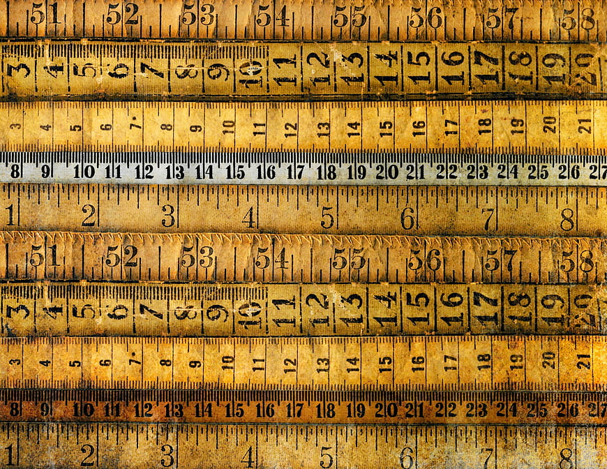 Vintage wooden rulers and measuring tapes stacked horizontally